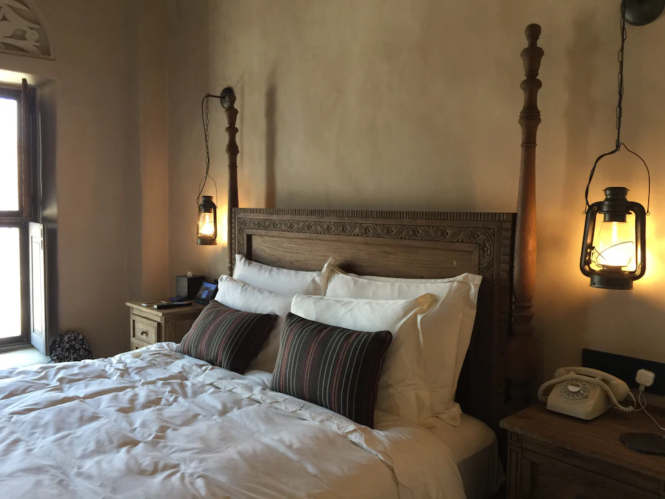 A traditional guest-house room with a carved wooden bed and lantern lights