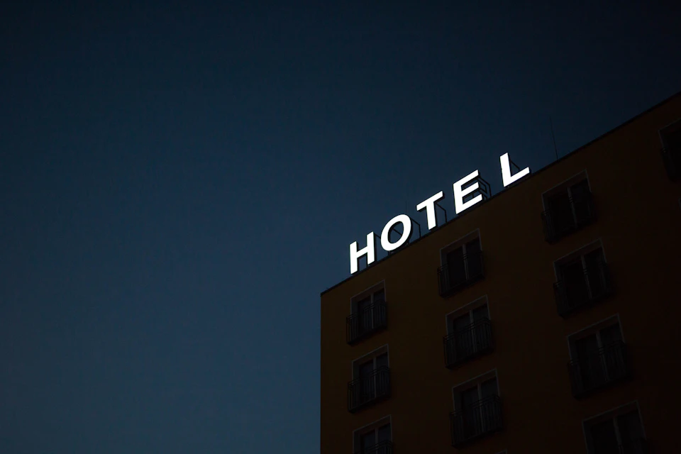 An illuminated HOTEL sign on a building facade against a deep blue evening sky